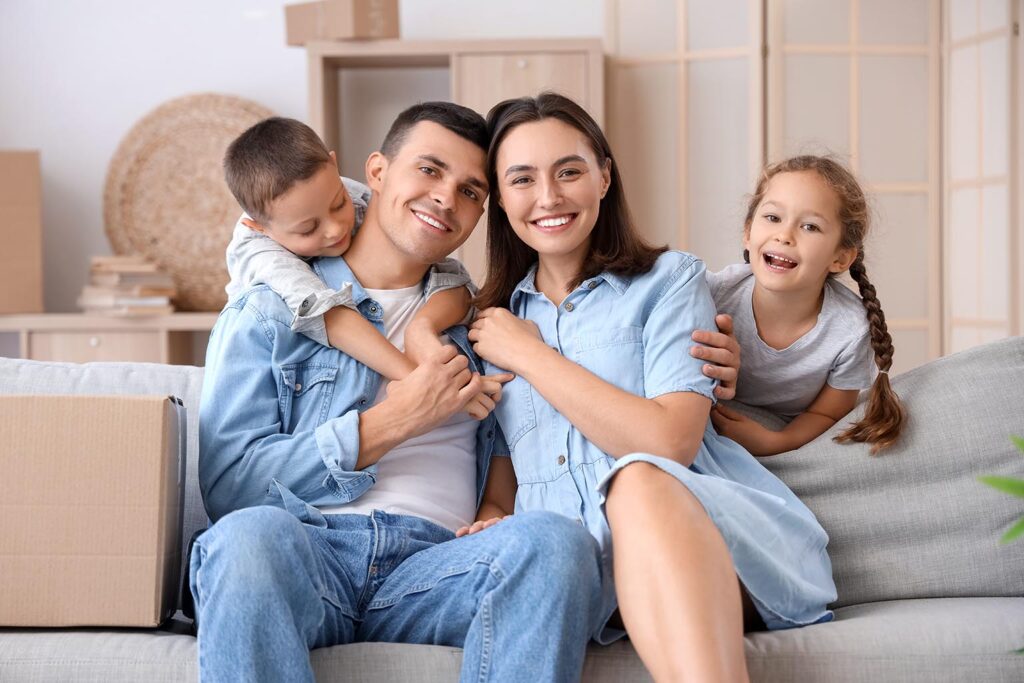 Младо щастливо семейство с деца седи на диван - отдаване под наем на имот