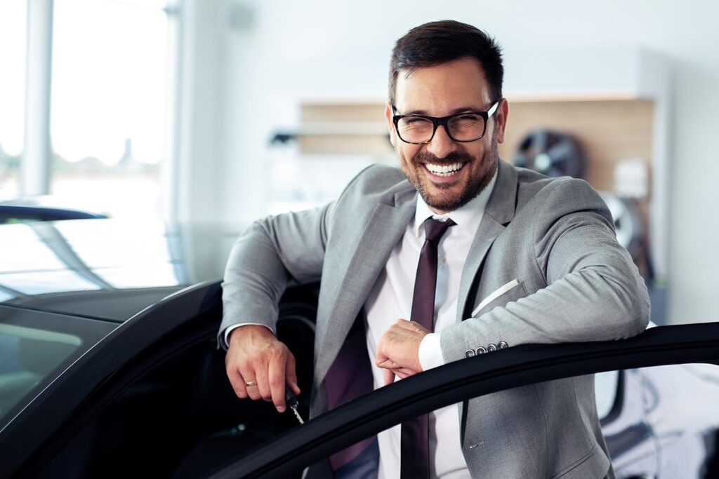 Усмихнат Trust properties служител се кани да влезе в кола за да отиде на среща с клиент.