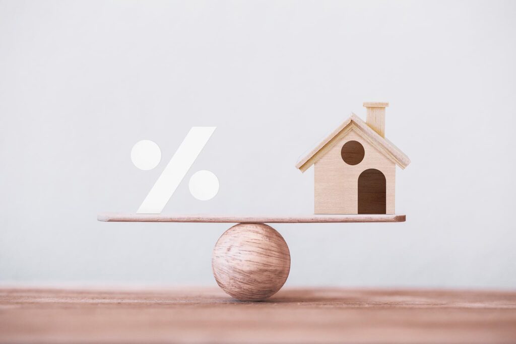 Знак процент в баланс с макет на къщичка - баланс между управление на имот и доходите от него